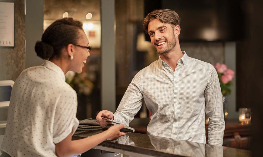 A-female-hotel-receptionist-taking-the-contactless-payment-of-a-customer